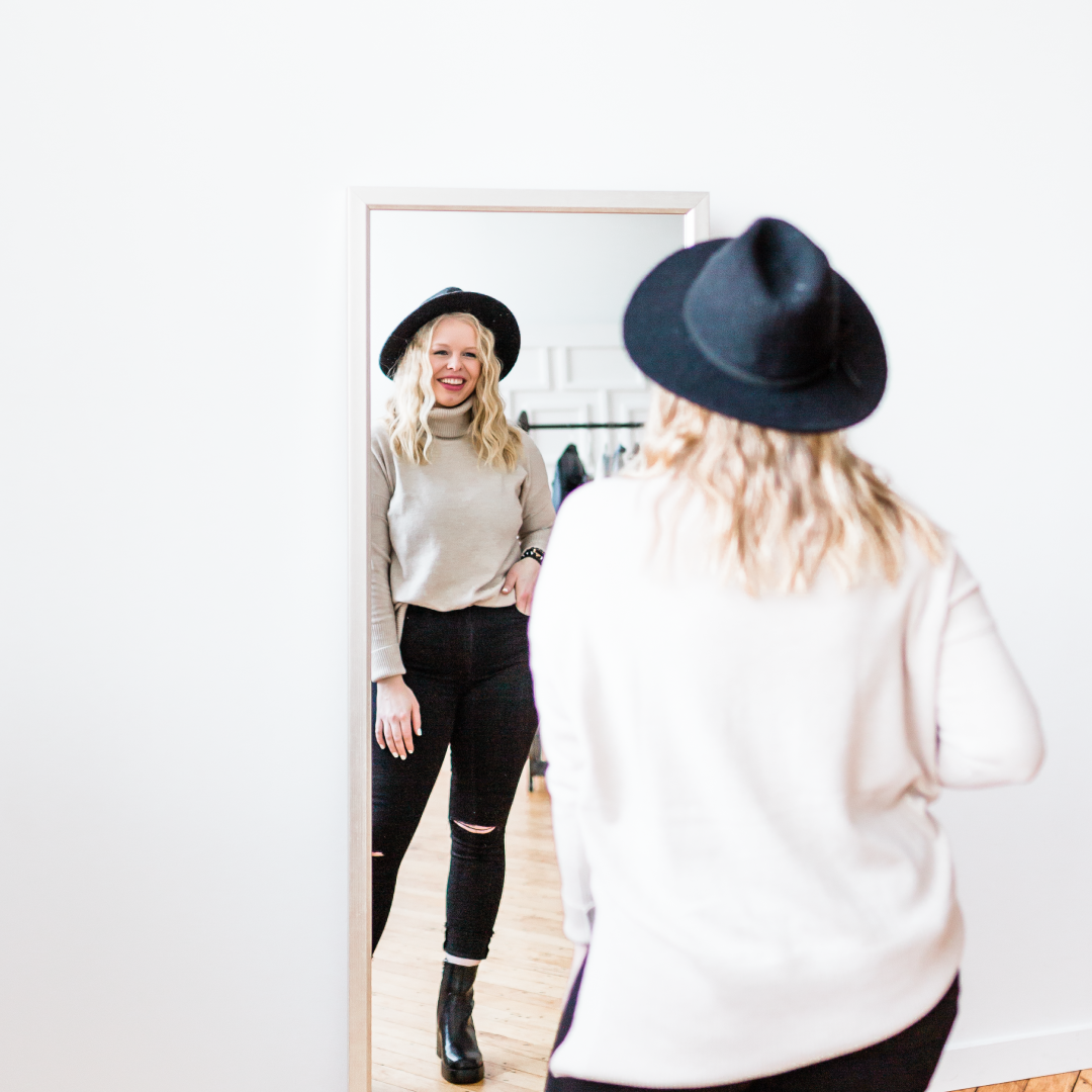 A personal stylist smiling in the mirror at herself.